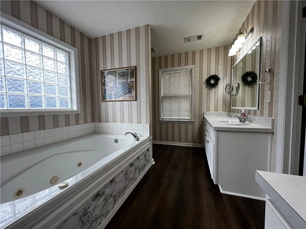 Indulge in a relaxing soak within this private bathroom featuring a jetted tub and rich flooring.