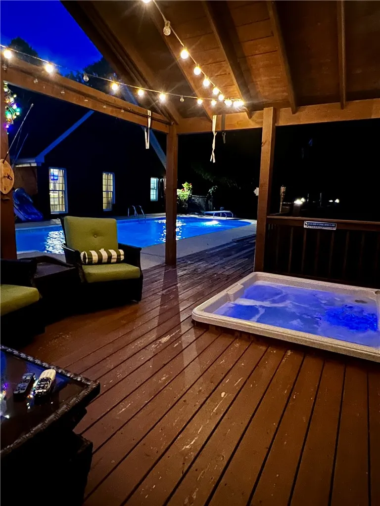 An inviting covered patio featuring a private spa and a sparkling pool, ideal for twilight relaxation.