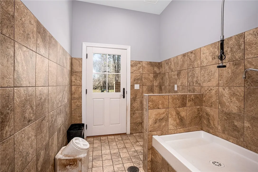 Dog shower/feeding room with outside access to fenced dog run.