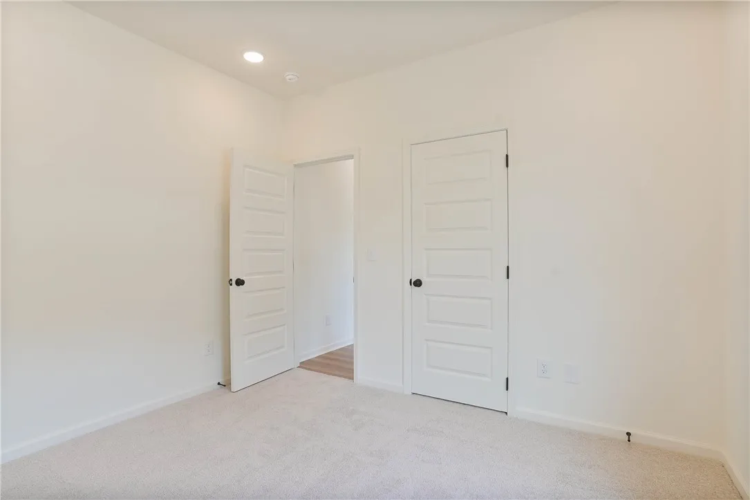 A well-lit bedroom with pristine carpet flooring and modern panel doors awaits your personal touch.