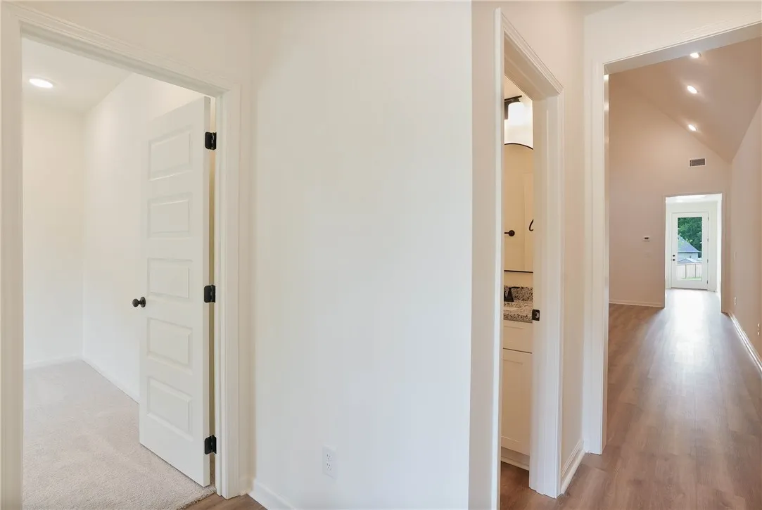 A well-lit corridor with recessed lighting leads to an outdoor view, highlighting the architectural flow.
