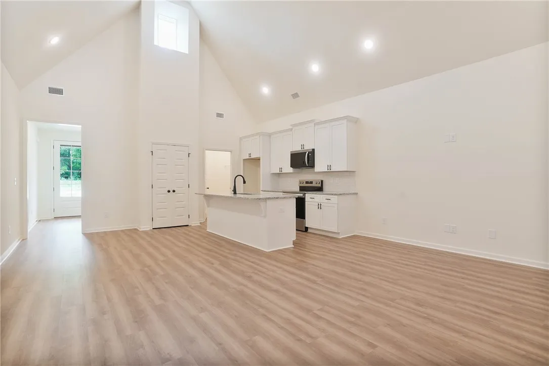 A well-lit open floorplan connects the kitchen and living spaces, featuring vaulted ceilings and abundant natural light.