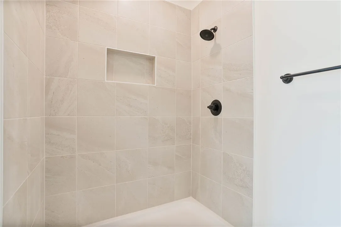 A well-appointed shower features light-toned tile work and modern dark bronze fixtures.