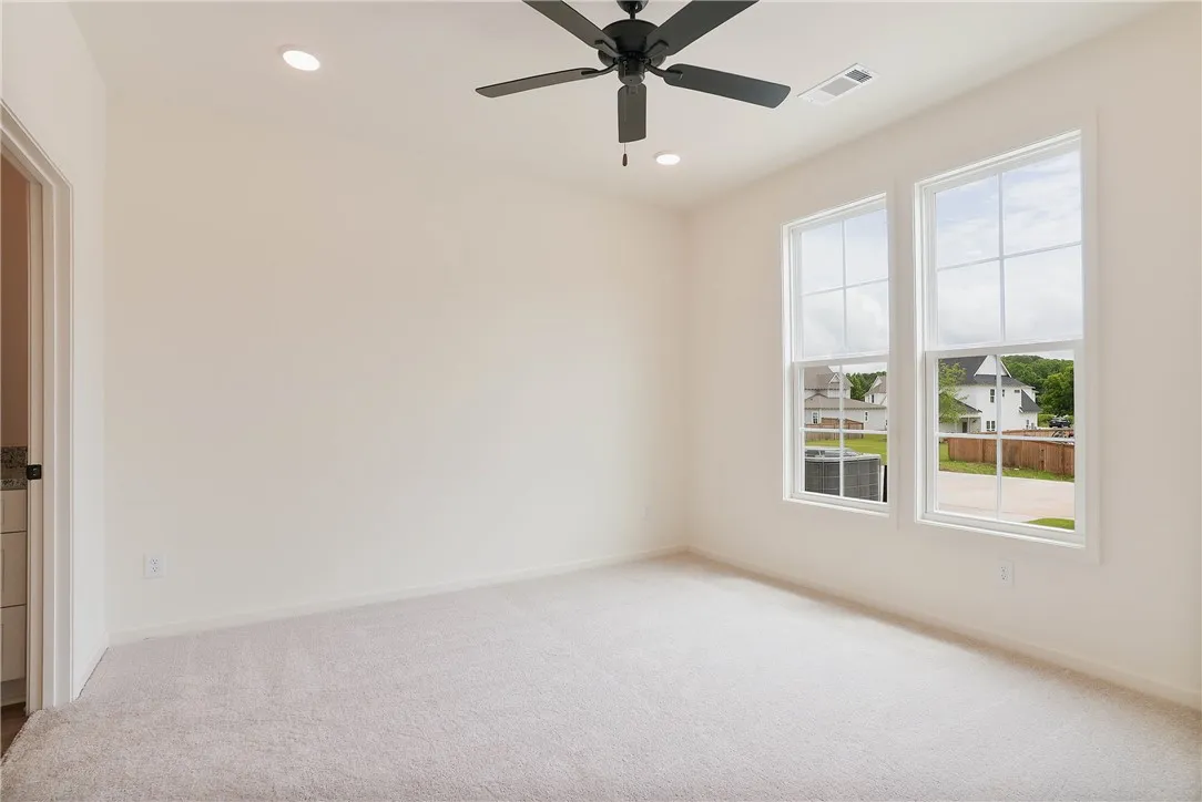 A quiet bedroom with ample light, complete with recessed lighting and a ceiling fan for comfort.