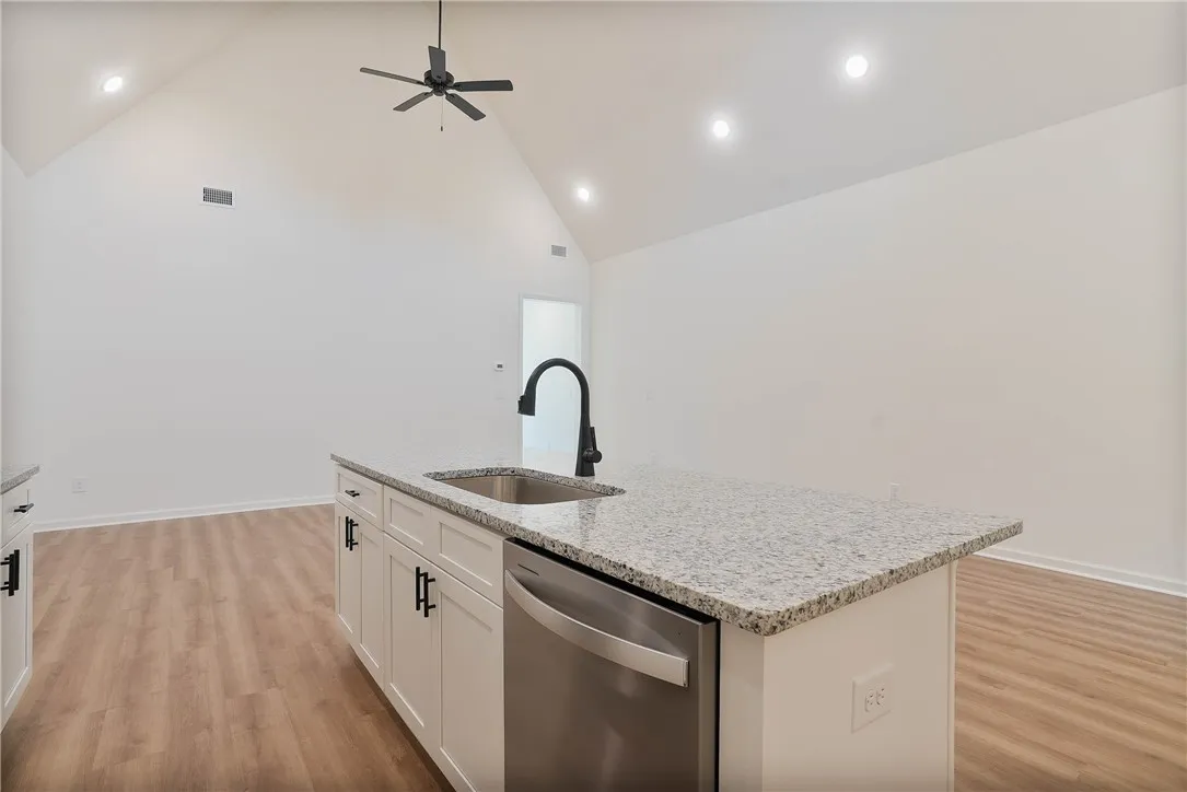 A streamlined kitchen island with a granite countertop and a dishwasher anchors this contemporary open-concept space.