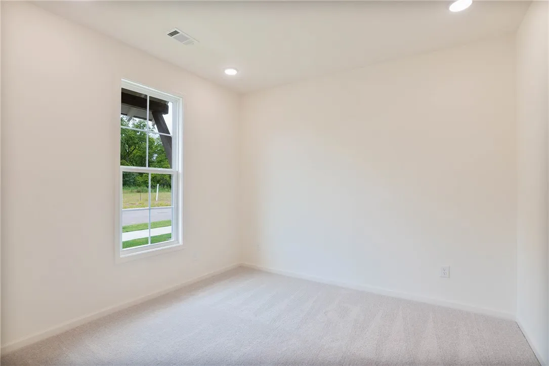 A well-lit bedroom with ample space for furnishings, offering a peaceful view of the outdoors.