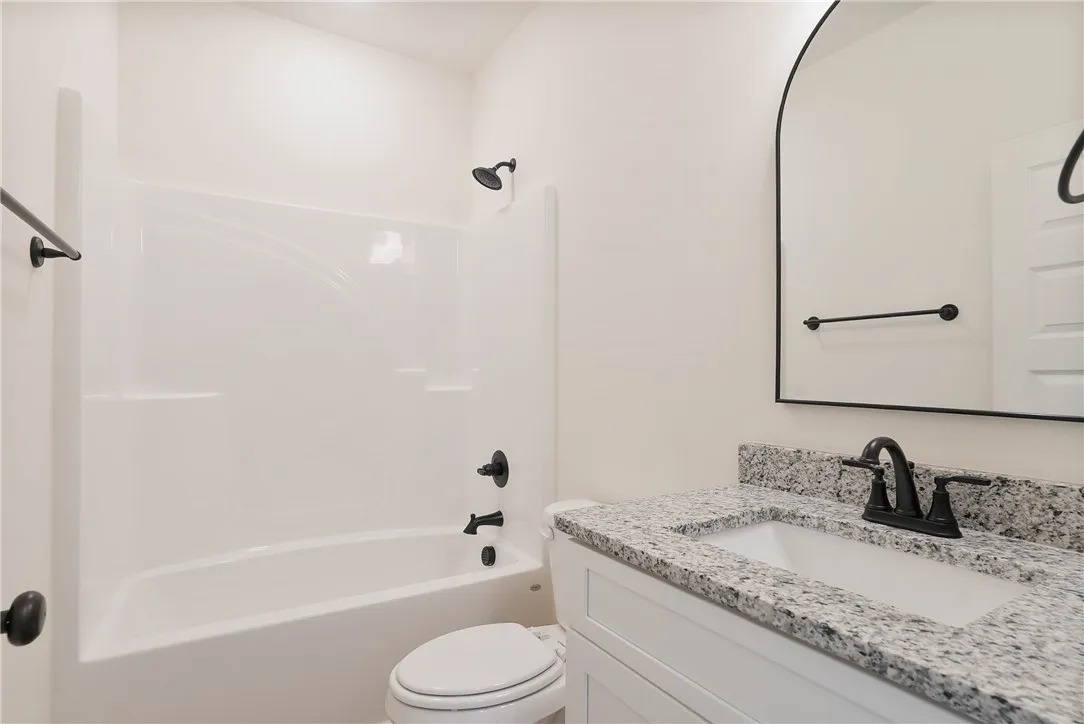 Granite counters and a clean tub/shower combo complete this fresh, well-appointed bathroom.