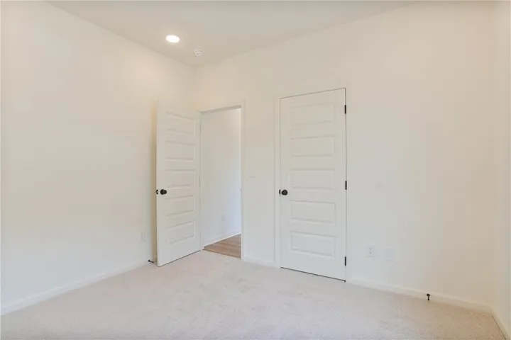 A well-lit bedroom with pristine carpet flooring and modern panel doors awaits your personal touch.