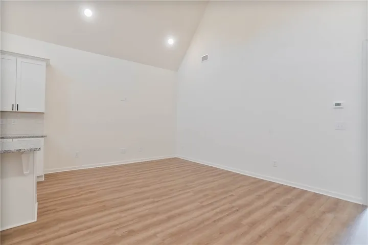 A grand living space features vaulted ceilings and light wood flooring, offering a contemporary open-plan feel.