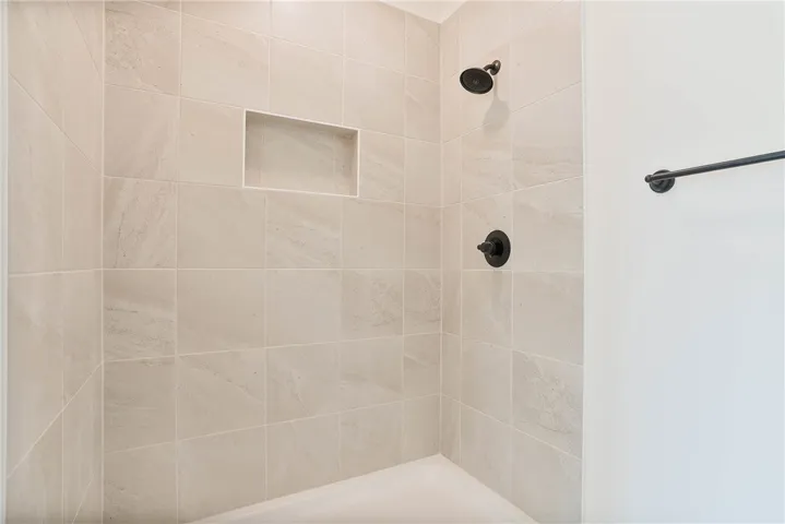 A well-appointed shower features light-toned tile work and modern dark bronze fixtures.