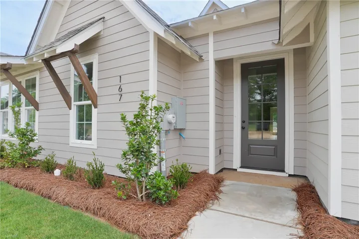 A welcoming entry features decorative wood accents, pristine landscaping, and an inviting front door.