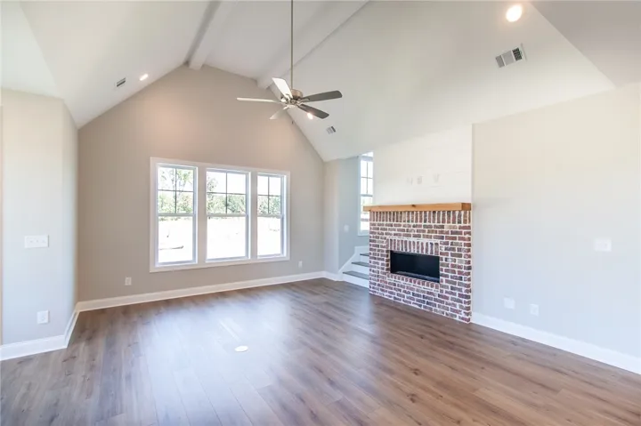 This expansive great room features vaulted ceilings, ample natural light, and a charming brick fireplace.