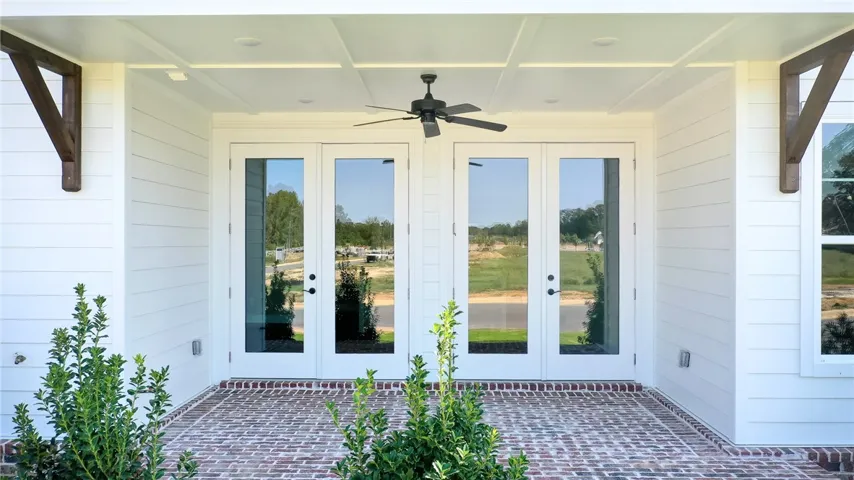 This inviting porch features classic brick flooring and elegant French doors, perfect for welcoming guests.