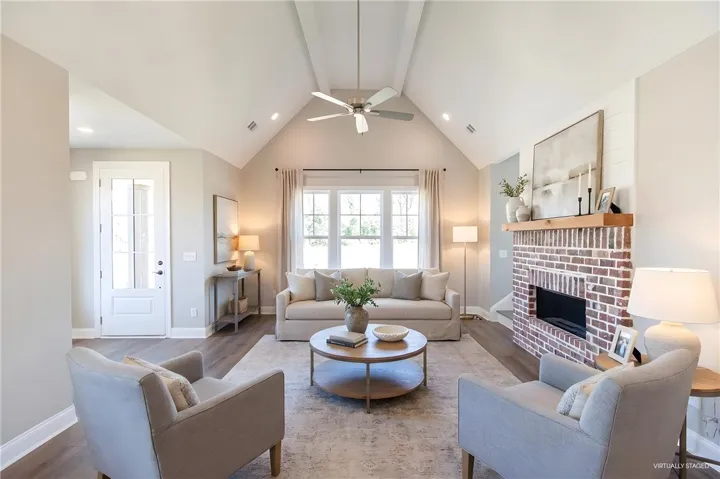 This bright living area features soaring vaulted ceilings and a charming brick fireplace.