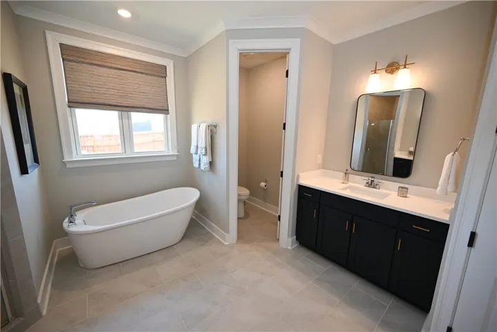 Quartz countertops, tiled shower, and water closet.
