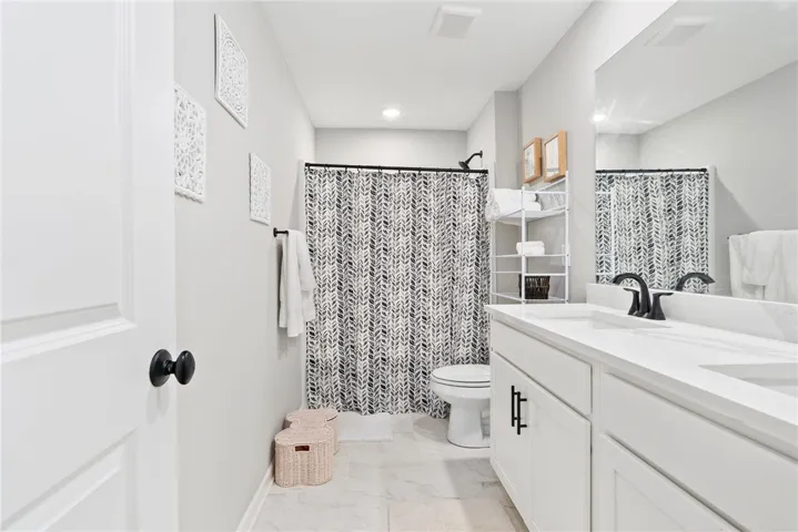 oversized guest bathroom upstairs with double vanity and marble tile