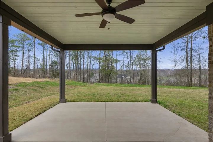 The covered porch provides an inviting outdoor living space, with added privacy thanks to neighborhood green space beyond the lot.