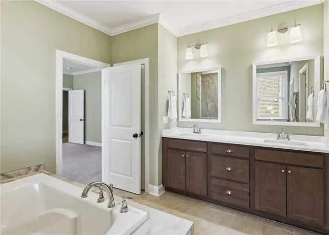 The exceptional primary bath features a large soaking tub, extended dual-sink vanity, linen closet, walk-in tiled shower, and a spacious closet.