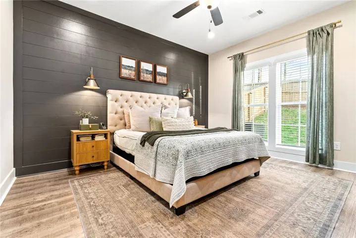 Primary bedroom with accent wall and upgraded sconces