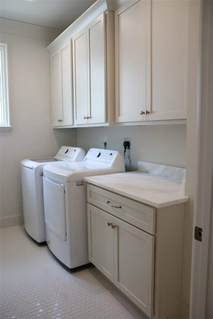 Functional laundry room offers upper and lower cabinetry with a practical countertop and modern appliances.