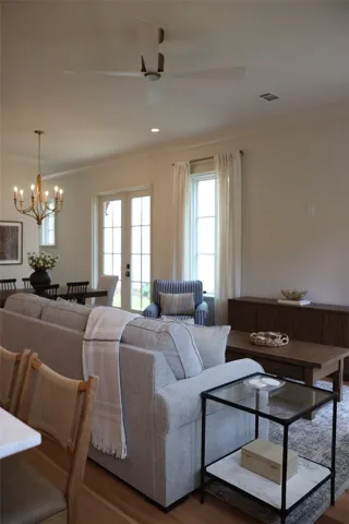 Natural light bathes this comfortable living space, featuring rich hardwood flooring and a stylish chandelier.