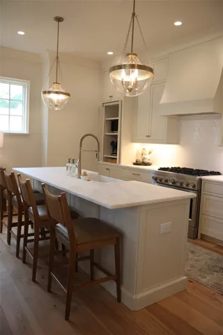 A gourmet kitchen boasts a spacious island with seating, a gleaming gas range, and stylish pendant lighting.