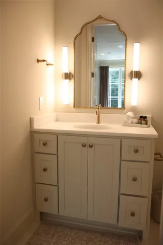 A well-appointed bathroom vanity features a classic gold-framed mirror and integrated storage.
