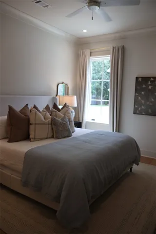 Well-lit sleeping quarters with a window overlooking the backyard and crown molding.