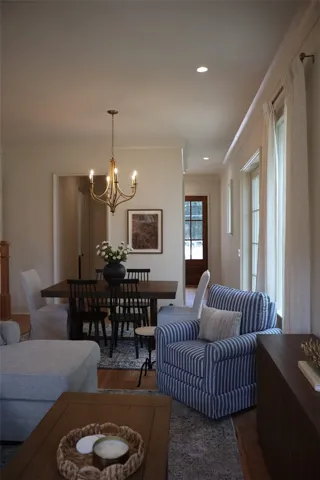 Hardwood flooring extends throughout this well-lit open floorplan, featuring an elegant chandelier over the dining area and recessed lighting.
