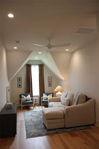 A cozy, well-lit sitting area under sloped ceilings features warm hardwood floors.