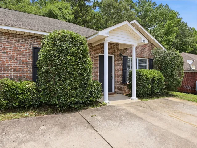 A welcoming brick exterior with a covered porch and mature, well-maintained landscaping.