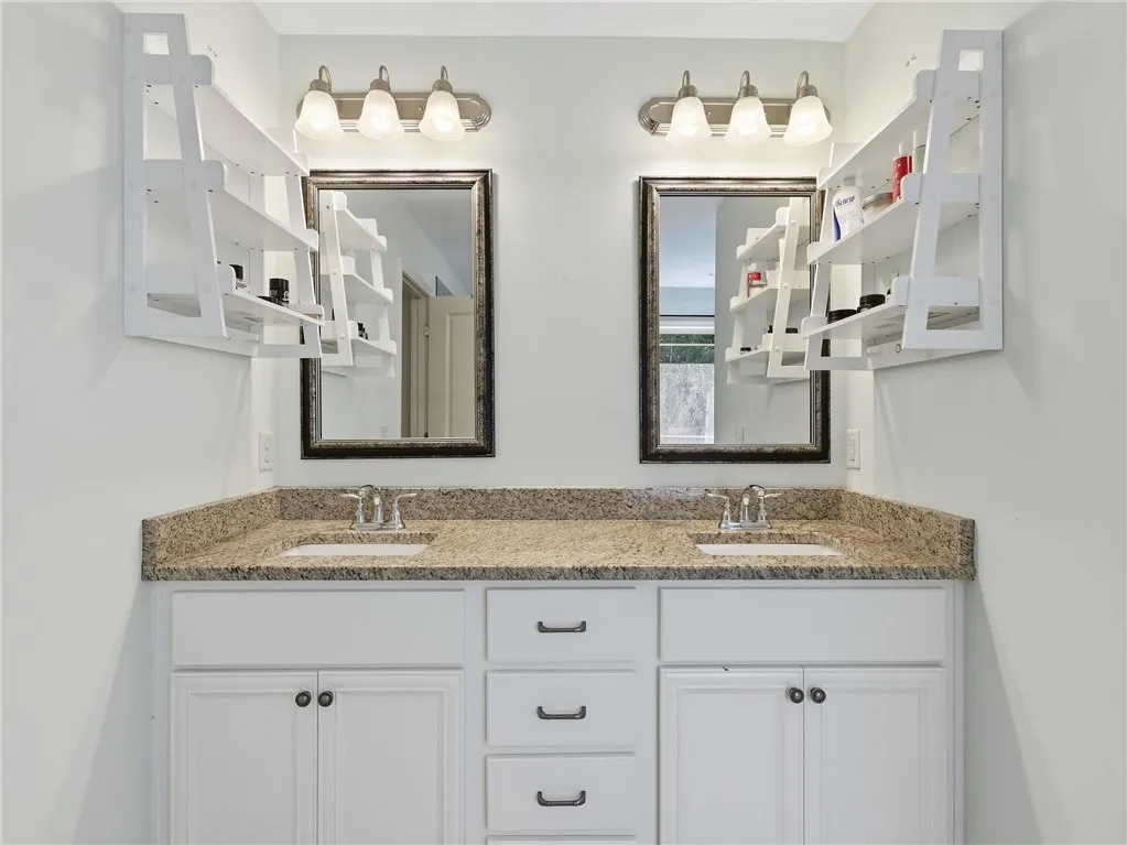 A well-appointed primary bathroom features a dual vanity with granite counters, offering ample space and convenience.