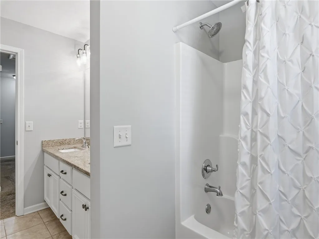 A well-appointed bathroom features a practical shower-tub combination alongside a vanity with granite counters.