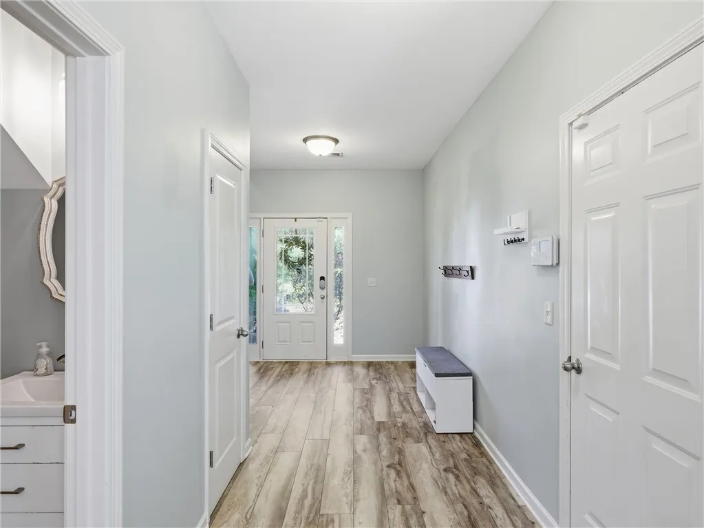 A well-lit entry hall with light-toned wood-look flooring and a decorative glass-paneled front door welcomes all.