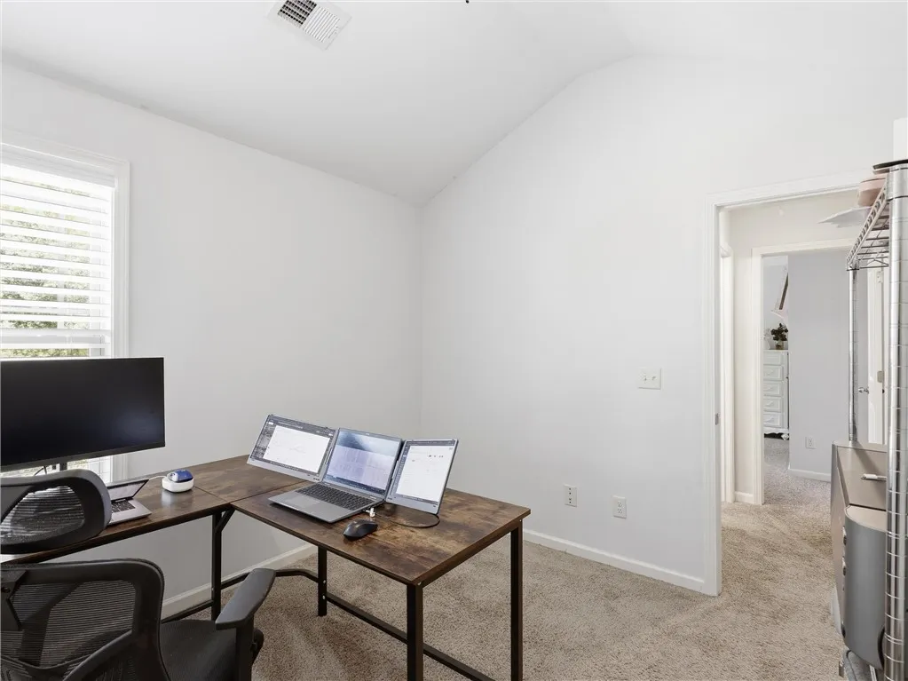 A quiet office space features vaulted ceilings and plush carpeting, perfect for productive workdays.
