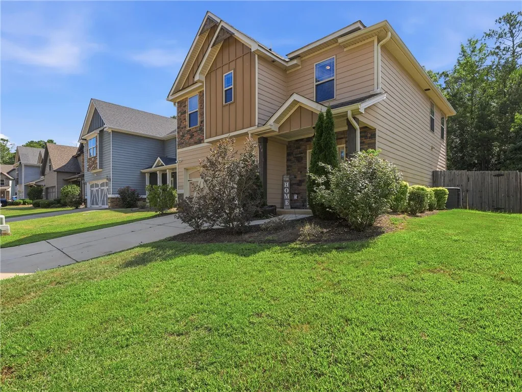 A well-maintained lawn and driveway lead to a inviting modern facade with a blend of siding and stone accents.
