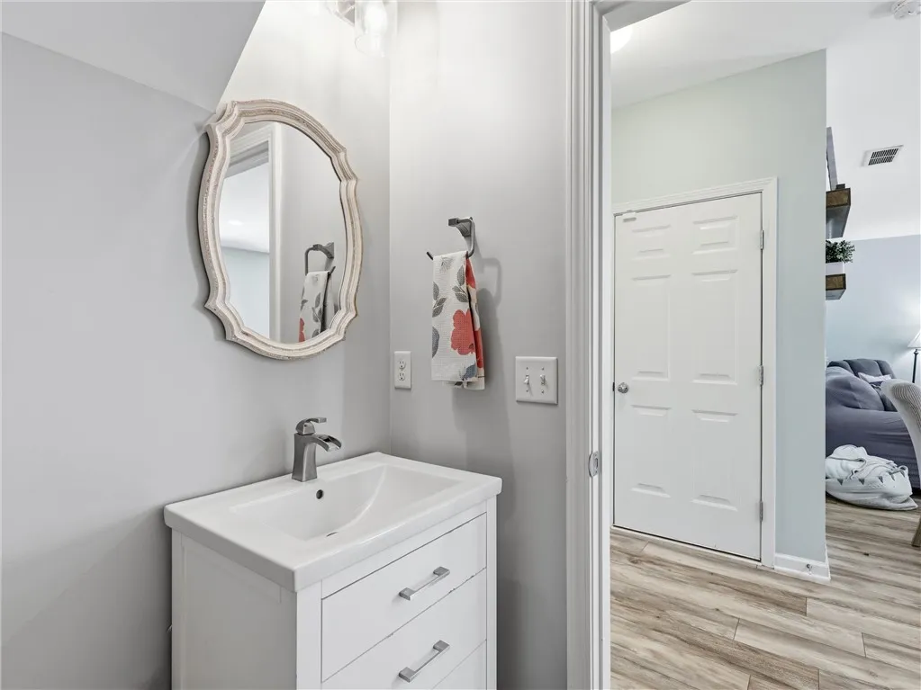 A well-appointed half bath features a stylish vanity and framed mirror, complementing the inviting plank flooring.