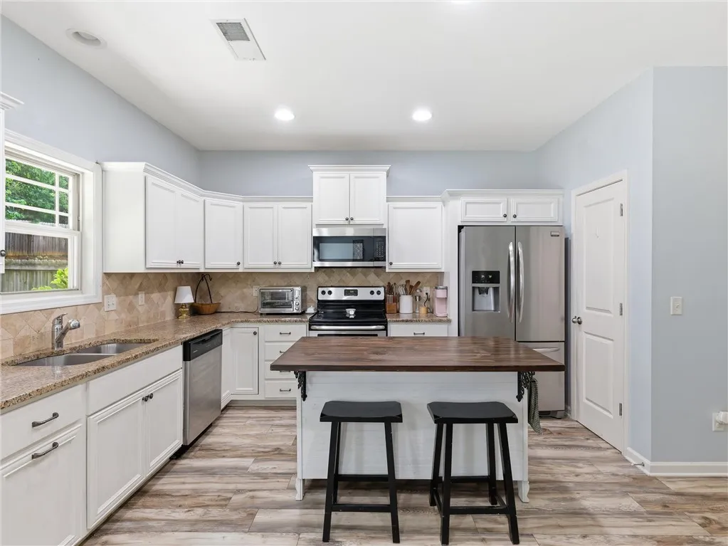 A well-lit kitchen presents a blend of functional design and inviting aesthetics, featuring ample cabinetry and a practical center island.