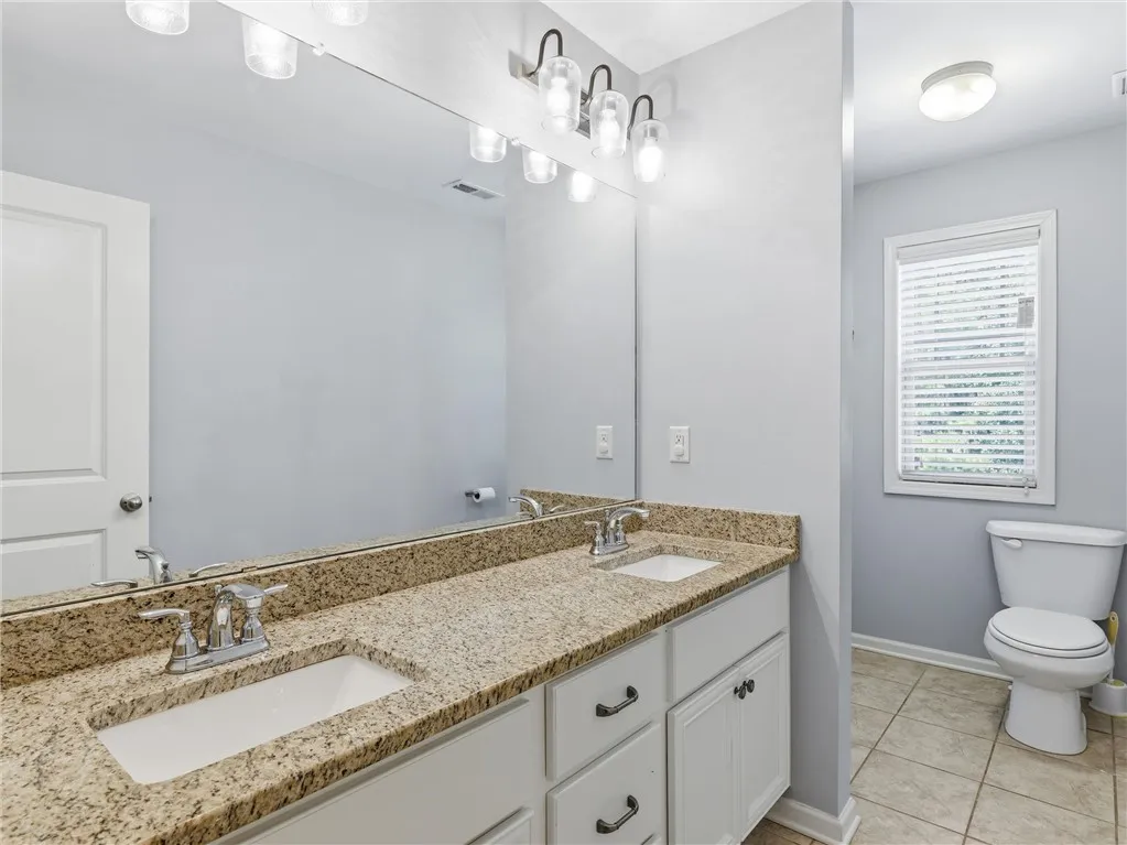 Double vanity with granite counters and expansive mirror anchors this functional bathroom space.