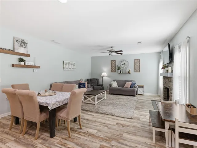 This naturally illuminated living area and dining space features durable wood-look flooring and a cozy fireplace.