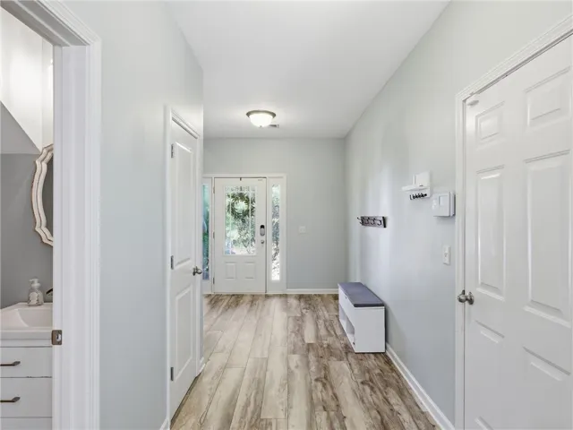 A well-lit entry hall with light-toned wood-look flooring and a decorative glass-paneled front door welcomes all.