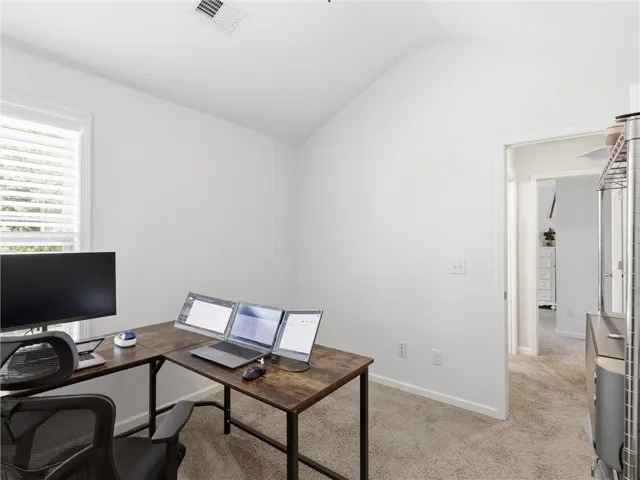 A quiet office space features vaulted ceilings and plush carpeting, perfect for productive workdays.