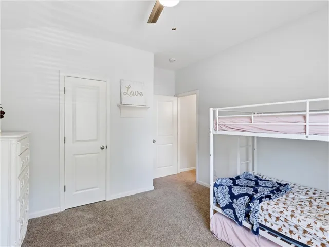A restful bedroom offers soft carpeting, a ceiling fan, and ample closet space.