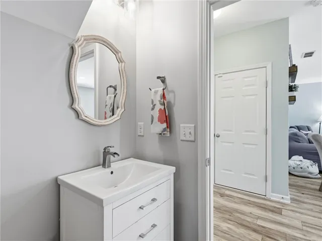 A well-appointed half bath features a stylish vanity and framed mirror, complementing the inviting plank flooring.