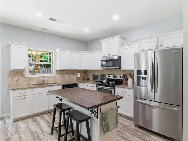 A well-appointed kitchen showcasing white cabinetry and contemporary appliances, centered around a charming island with bar seating.