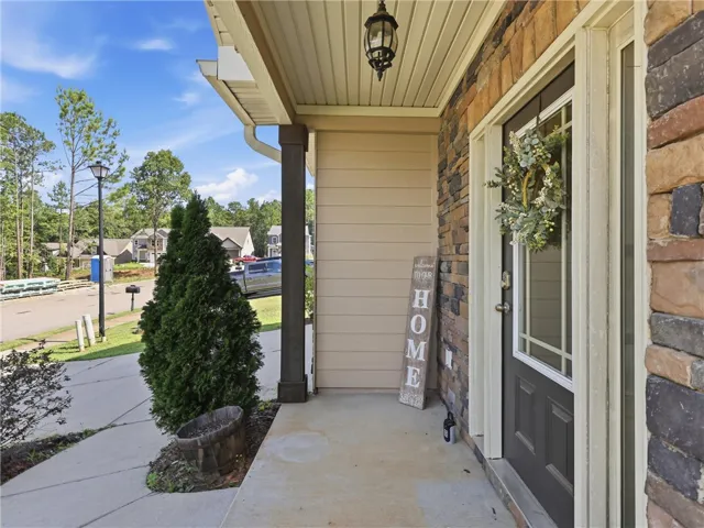 A welcoming front porch features elegant stone siding, a sturdy column, and a charming front door.