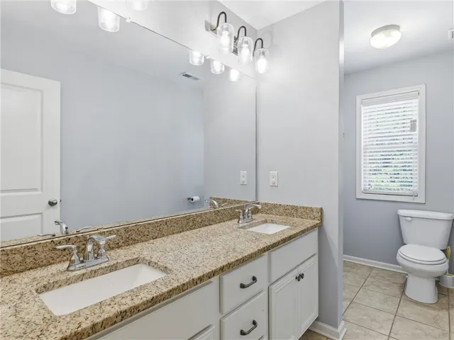 Double vanity with granite counters and expansive mirror anchors this functional bathroom space.