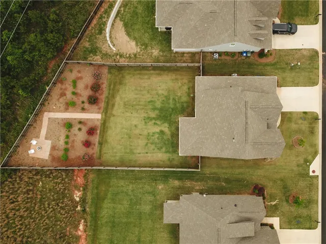 This expansive aerial view showcases a vibrant green yard with a dedicated fire pit area.