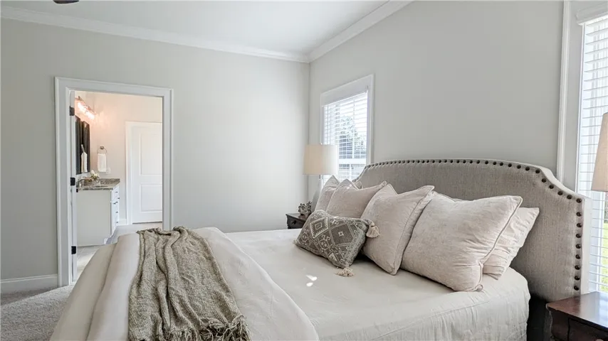 Light-filled primary bedroom with en-suite bath in background.