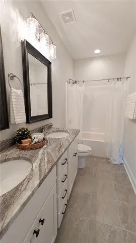 Main level hall bath featuring dual sinks and linen closet.